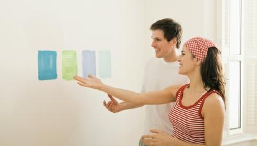 A couple compares paint samples on a white wall. A couple compares paint samples on a white wall.