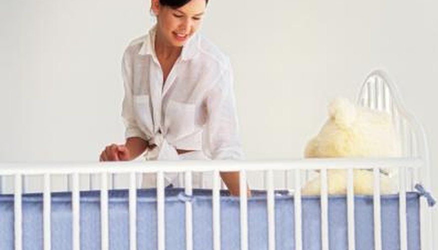 Young mother looking over a standard crib. Young mother looking over a standard crib.