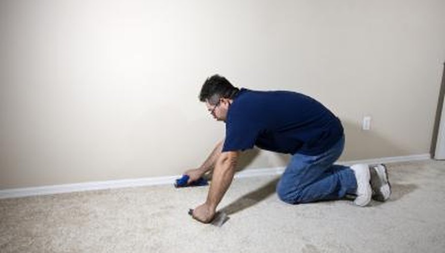 Professional carpet installer works to remove old carpet entirely Professional carpet installer works to remove old carpet entirely