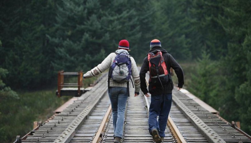 Two people hiking along a wooden rail road track. Two people hiking along a wooden rail road track.