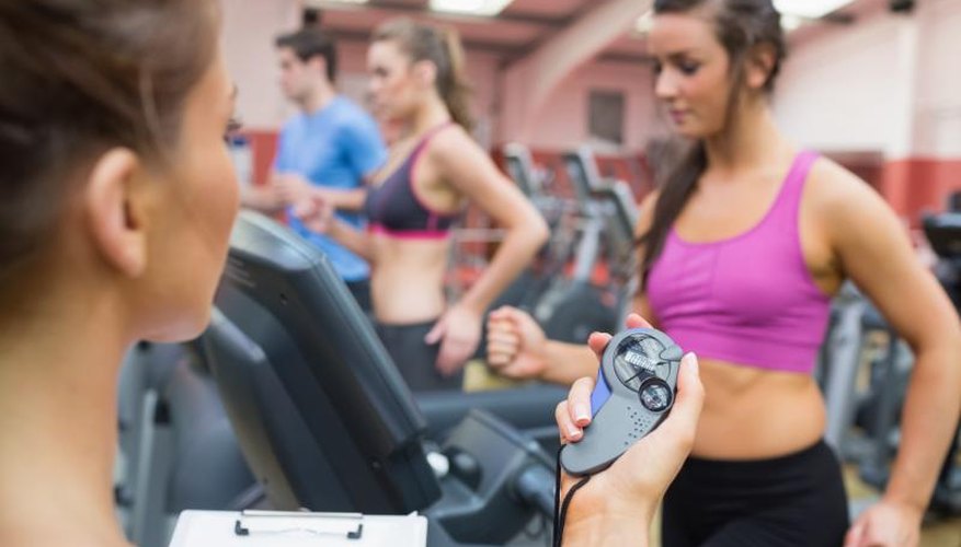 A fitness instructor uses a stopwatch while training a client with HIIT. A fitness instructor uses a stopwatch while training a client with HIIT.